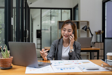 Charming asian businesswoman in black shirt talking by mobile phone in office