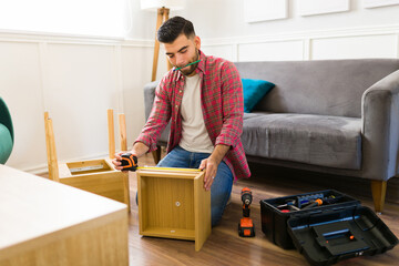 Handsome man measuring a table while building new furniture