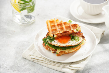 Savory breakfast - fresh homemade belgian waffle sandwich with green lettuce, crisp bacon and fried...