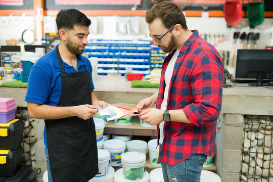 Caucasian Young Man Shopping For The Best Color Paint At The Hardware Store