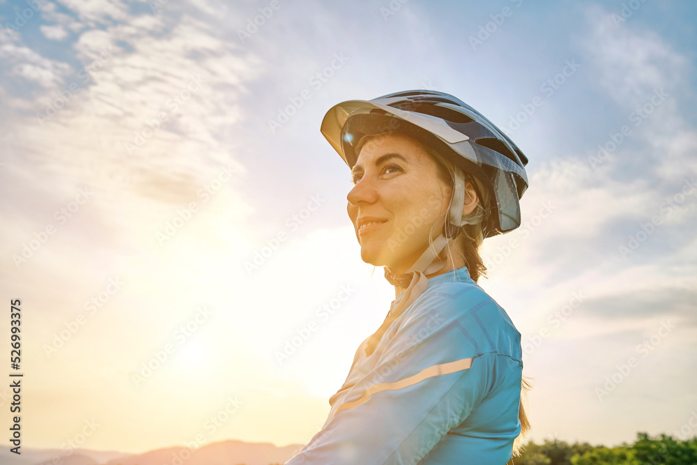 Wall mural Cyclist Woman riding bike in helmets go in sports outdoors on sunny day a mountain in the forest. Silhouette female at sunset. Fresh air. Health care, authenticity, sense of balance and calmness.