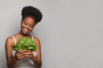 Happy black woman with greens on white banner background. Healthy eating concept