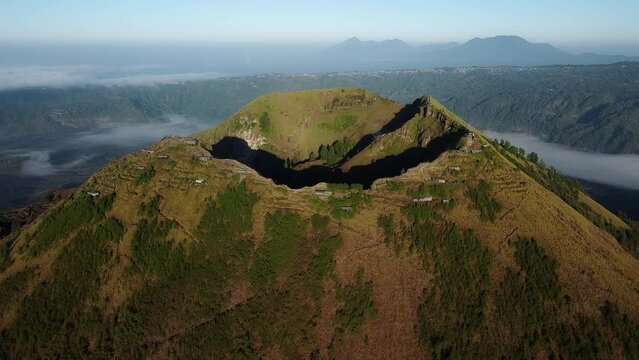 Batur volcano crater on Bali Island. With green forests on the volcano. Drone view.