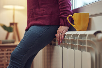 Woman heating on a chilly winter day, energy and gas crisis, cold room, heating problems.