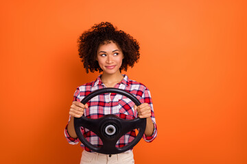 Portrait of attractive trendy cheerful girl holding steering wheel copy blank space ad isolated over bright orange color background