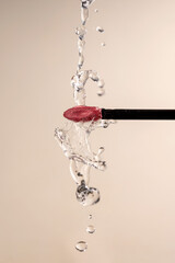 Pink liquid lipstick applicator brush and water drops. Waterproof liquid lipstick brush