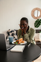 Young beautiful smiling african woman lunch while working with laptop