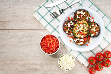 Homemade grilled eggplant with feta and tomatoes on a white table, top view. Flat lay, copy space for text.