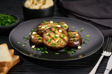 Homemade grilled eggplant with parsley and garlic  on a black table.