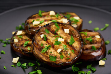 Organic roasted grilled eggplant with parsley and garlic close up.