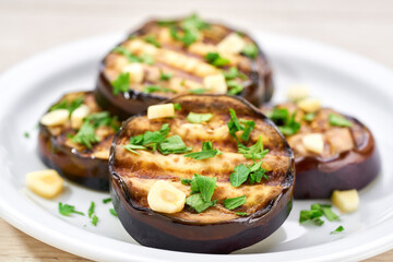 Organic roasted grilled eggplant with parsley and garlic close up.