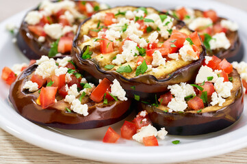 Salad with grilled eggplant, feta and tomatoes on a white plate,selective focus.