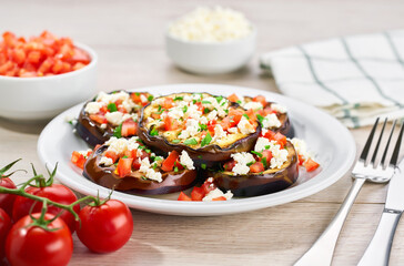Grilled eggplants with cheese, cherry tomatoes and species on white table.
