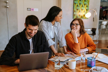 Multiracial young colleagues discussing project while working in office