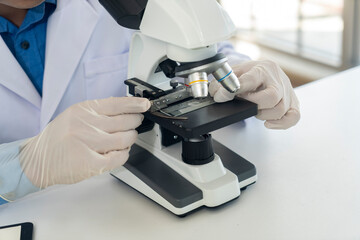 Handsome scientist man wearing rubber gloves working with microscope