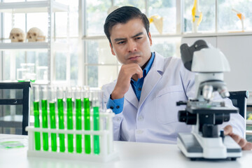 Young male researcher analyzing liquid in tube at laboratory