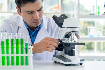 Young male researcher analyzing liquid in tube at laboratory
