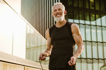 Mature gray sportsman using jumping rope during workout outdoors