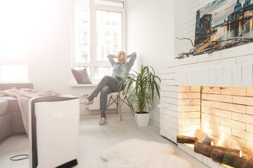 Woman at home in a clean and safe environment from virus by air purifying filter.