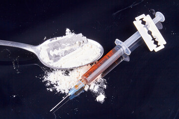 Close-up spoon with drugs powder and syringe with razor. Drug use concept. Dangerous heroin...