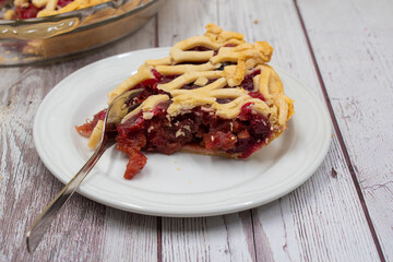Apple Cranberry Pie home baked in glass dish, white wooden table, pie slice