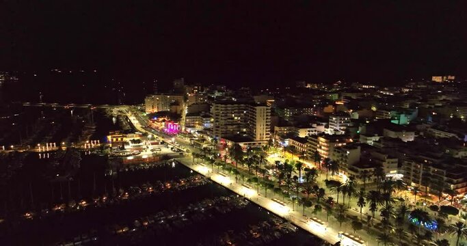 City lights at night, facing the marina of Ibiza. Aerial video of the skyline and the streets full of vehicles.