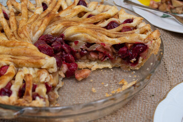 Apple Cranberry pie  sectionon burlap cloth, wooden white table