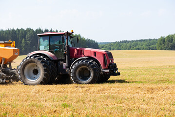 Tractor on the field harvests.