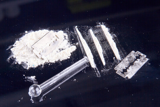 White powder drugs with razor and smoking pipe. Drug use concept.
