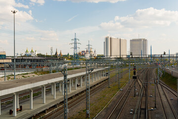 Fototapeta na wymiar Rails and platform of the Vostochny railway station in Moscow. Izmailovsky Kremlin and hotels in the background.
