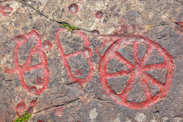 Wheel and footprints petroglyphs on a cliff