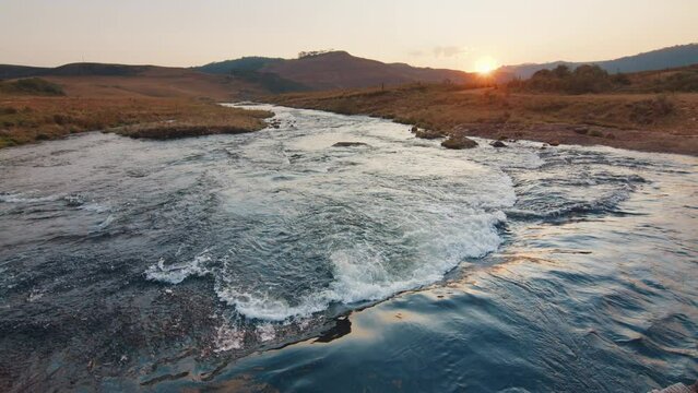 Rapid river flows in Brazilian mountains at sunset