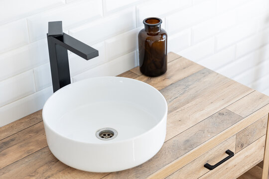 Black faucet for water and white separate high sink on wooden pedestal, top view. Loft style bathroom