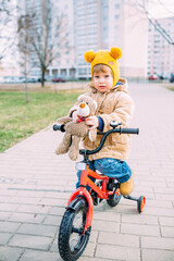 Fototapeta premium A small child learns to ride a bike for the first time in the city in spring