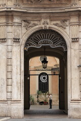 Sculpted Building Entrance with Lantern and Standing Man in Rome, Italy