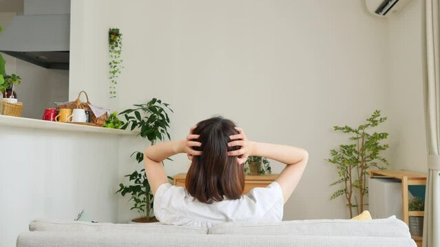 リビングで頭を抱える女性の後ろ姿