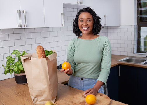 A young multi-racial woman unpacks her grocery shopping in the kitchen