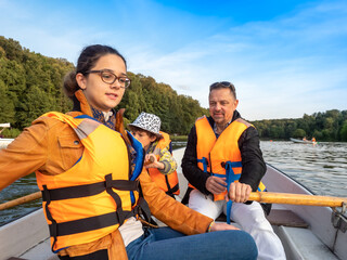 Friendly caucasian family floating on kayak with paddles. Concept of family rest, leisure and weekend at nature. father and daughter wearing life vests. autumn sunny day.Selective focus