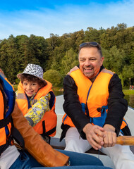 Friendly caucasian family floating on kayak with paddles. Concept of family rest, leisure and weekend at nature. father and daughter wearing life vests. autumn sunny day.Selective focus