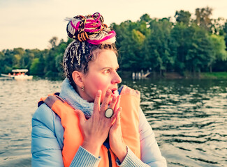 Middle aged woman with fancy hair wearing nautical lifejacket scared and amazed with open mouth for surprise, shocked face. Frightened girl at the lake