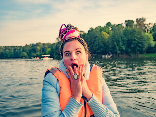 Middle aged woman with fancy hair wearing nautical lifejacket scared and amazed with open mouth for...