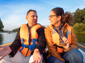 daughter teenager on boat with dad in life jackets in summer on lake. Family having fun laughing