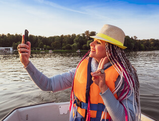 Woman taking picture of herself on smartphone during floating on kayak. Concept of rest, leisure and weekend. Middle Age Woman wearing life vests. Sunny autumn daytime.selective focus