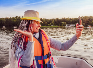 Woman taking picture of herself on smartphone during floating on kayak. Concept of rest, leisure and weekend. Middle Age Woman wearing life vests. Sunny autumn daytime.selective focus