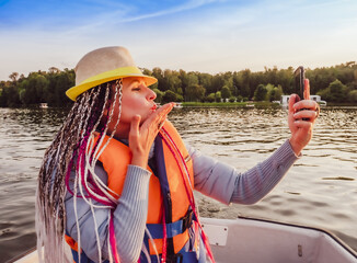 Woman taking picture of herself on smartphone during floating on kayak. Concept of rest, leisure and weekend. Middle Age Woman wearing life vests. Sunny autumn daytime.selective focus