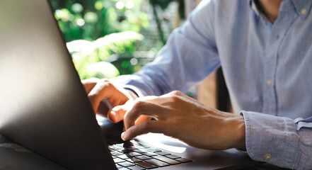 Obraz premium Young male working on the laptop in outdoor natural garden office. Developer solving problem, accountant calculating copy space banner photo summertime season.