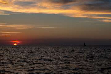 samotny jacht płynący po Zatoce Gdańskiej na tle zachodzącego słońca
