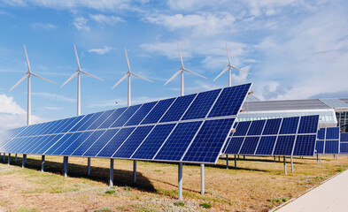 Set modern solar panels and wind turbines combined into station against blue sky