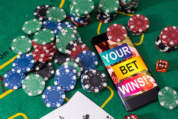 Online poker concept. Smartphone and poker chips on a green background. Poker online banner. Copy space. Vignette. Place for text. Gambling. Background