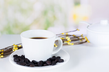 international coffee day, traditional colombian drink, close-up of mug and roasted coffee beans on the white kitchen table decorated with flowers